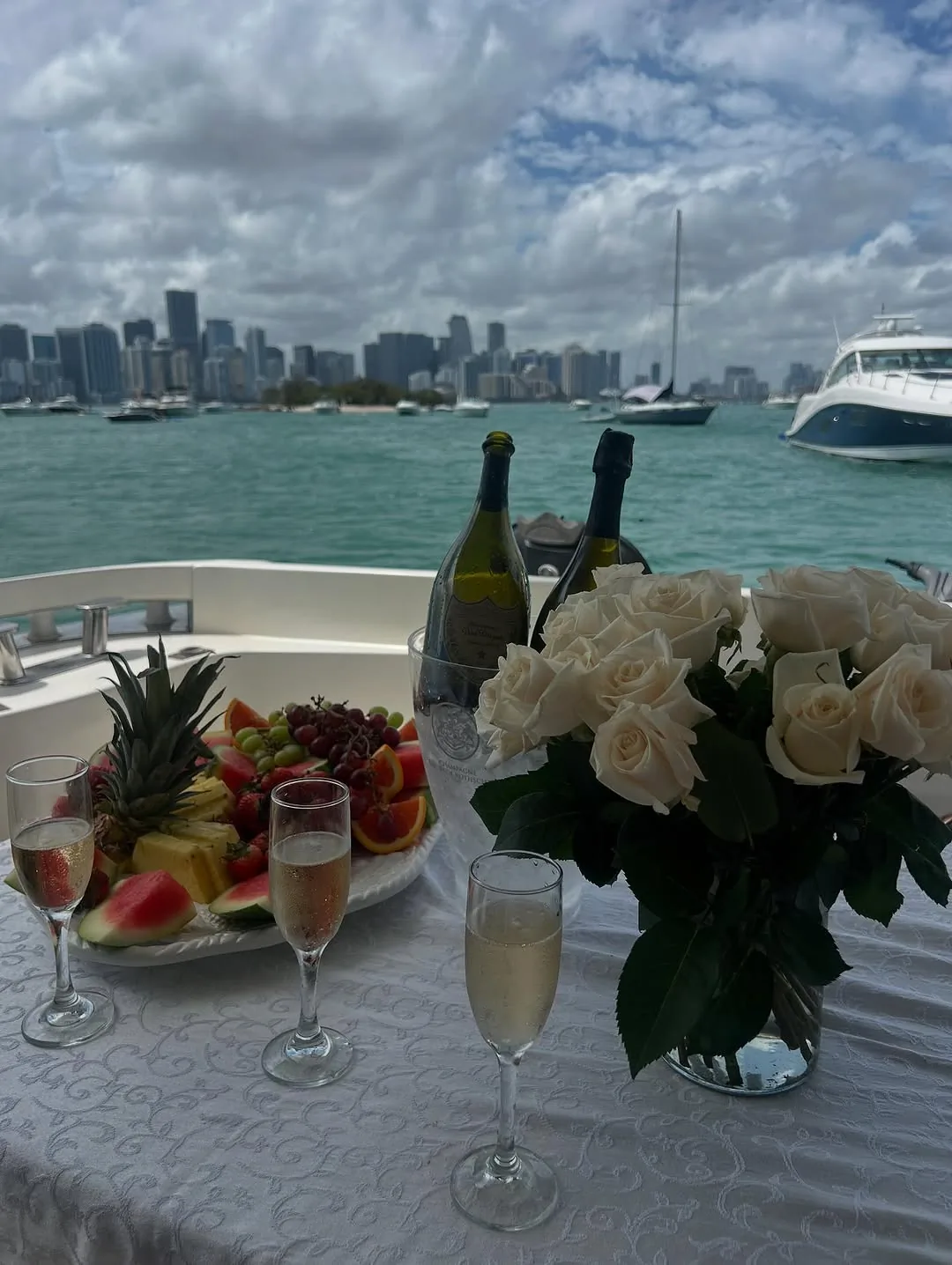 Champagne, fresh fruit, and white roses set up on the Pink Panther with the Miami skyline behind